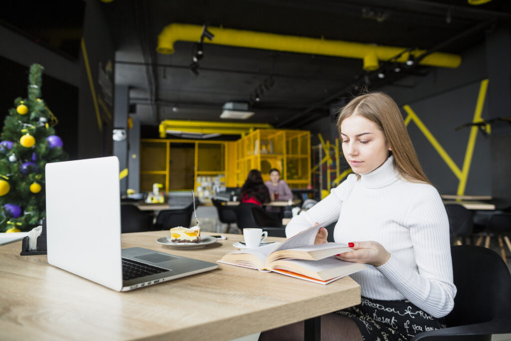 A modern woman working on a laptop at a clean workspace with office desks in a contemporary setting.