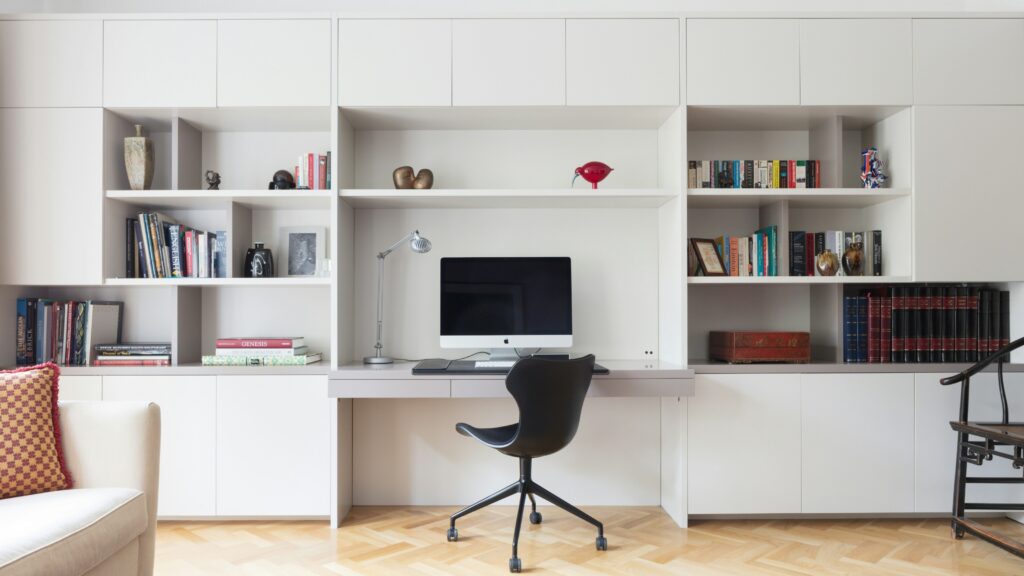 Black rolling office chair beside a white wooden shelf in a modern home office